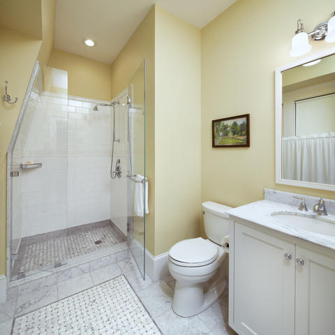 Bathroom with white tiling and stand-up shower, toilet, and vanity with cabinetry under the sink
