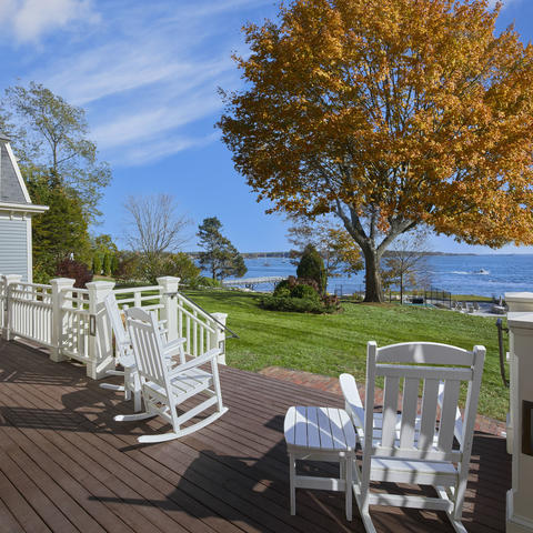 the patio facing the ocean view, complete with rocking chairs and an expansive green backyard