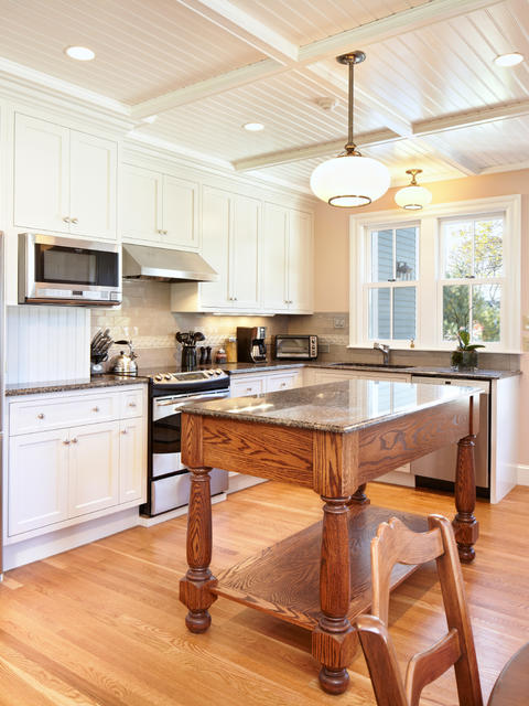Kitchen area with island, stainless steel appliances, overhead lighting, a small seating area, and bright windows with a door to the outside