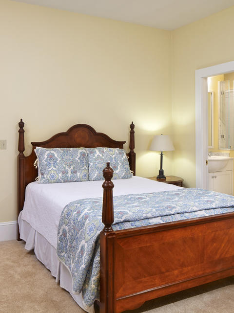 Bedroom with a full sized bed and en-suite bathroom in view, with a dresser and vanity area