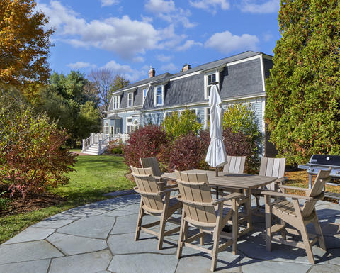Outdoor seating/dining area on a sunny day, surrounded by lush greenery on flagstone